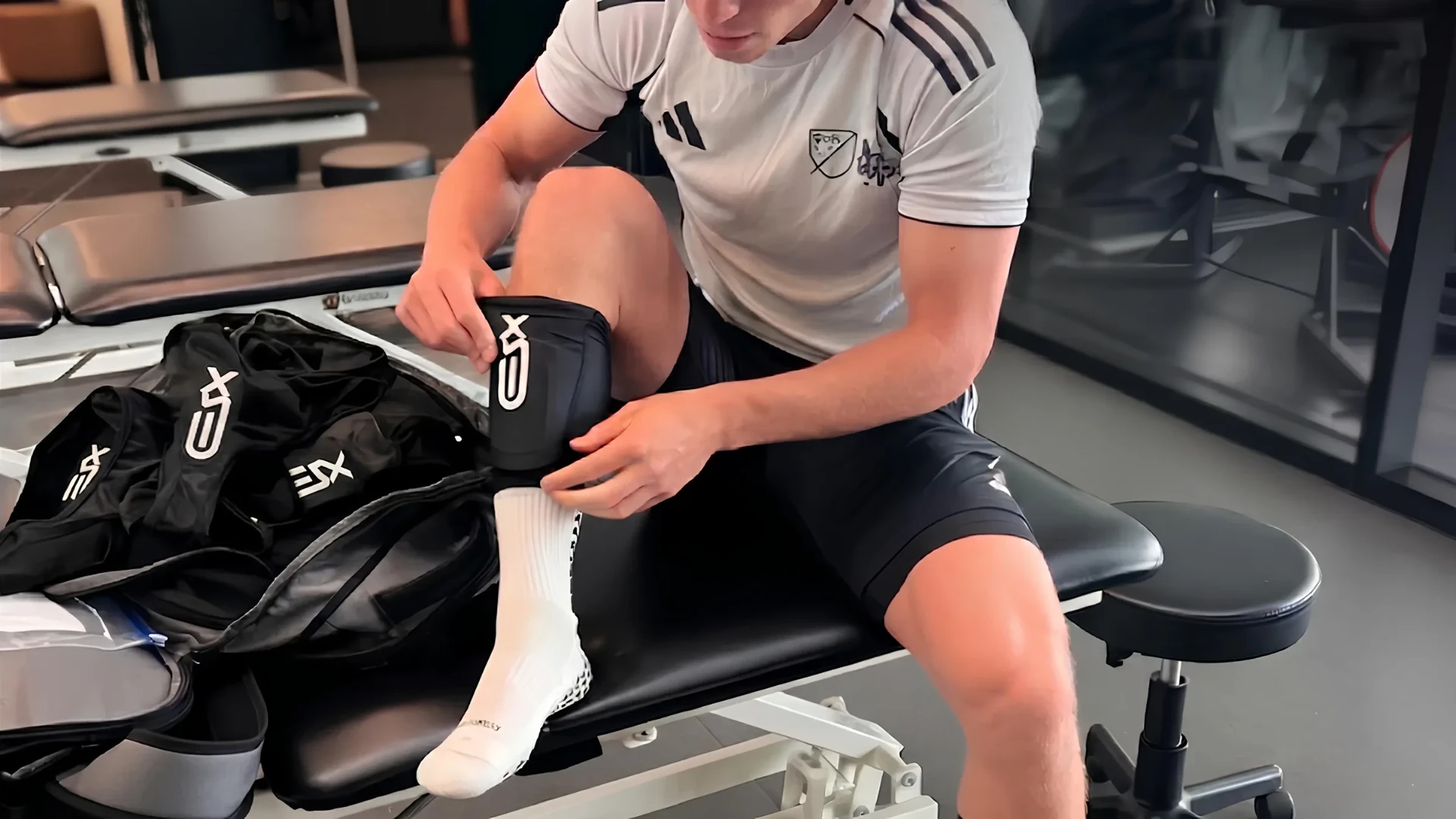 MLS NEXT player fitting an XSEED smart shinguard, with a kit bag of XSEED shinguards beside him, during the MLS Innovation Lab programme